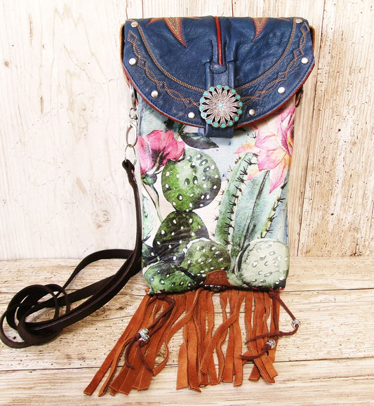 Floral and cactus-patterned handbag with denim top and fringes on a wooden surface