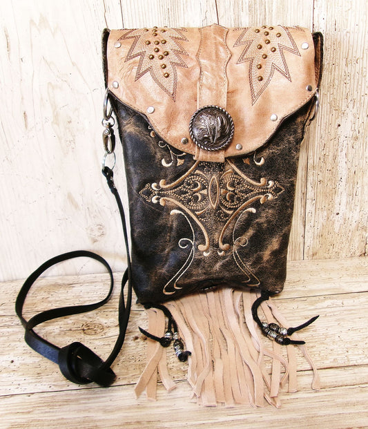 Decorative leather bag with intricate designs on a wooden surface