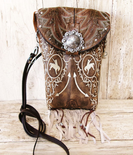 Brown leather bag with intricate white patterns and decorative elements on a wooden surface