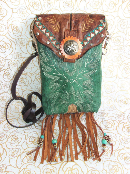 Green leather handbag with brown fringe and decorative elements on a patterned background