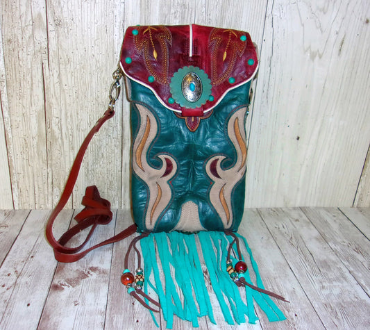 Leather handbag with turquoise fringes and decorative elements on a wooden surface.