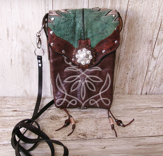 Brown leather crossbody bag with decorative elements on a wooden surface