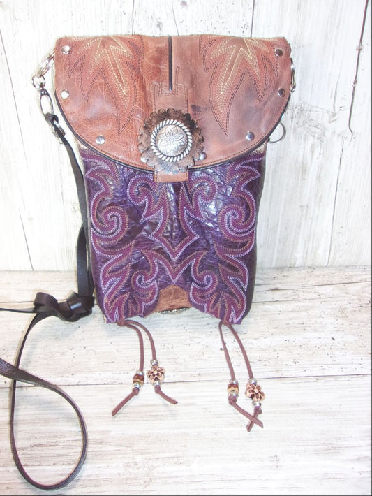 Leather handbag with purple pattern and silver concho on a wooden surface