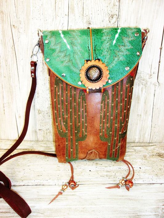 Green and brown leather bag with cactus design on a wooden surface