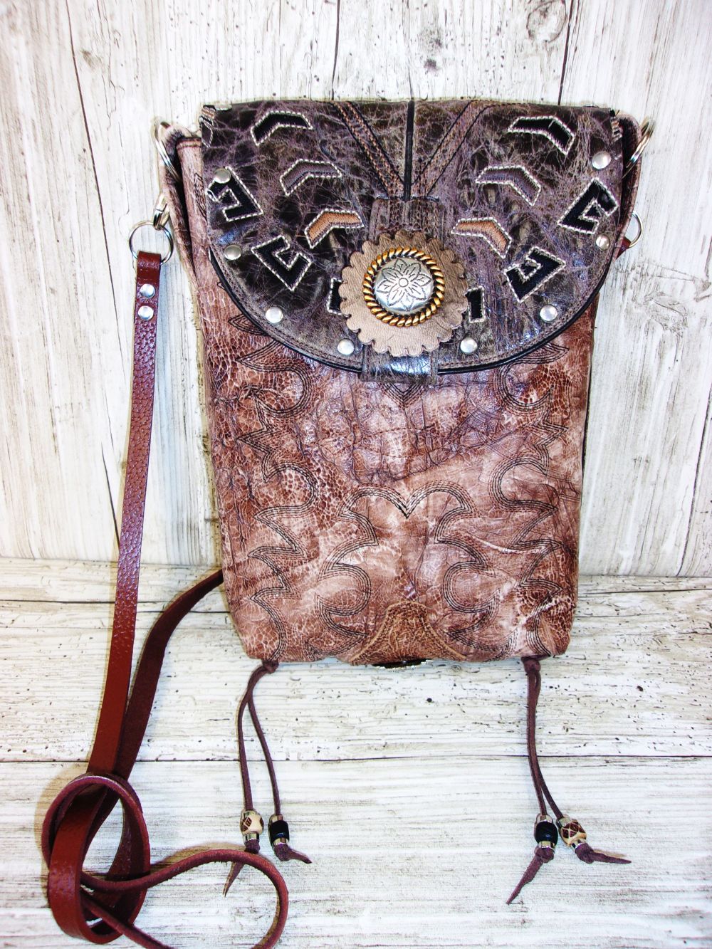 Brown leather bag with decorative elements on a wooden surface