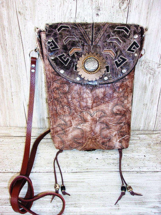 Brown leather bag with decorative elements on a wooden surface
