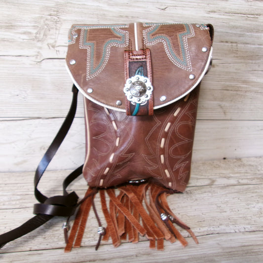 Brown leather small purse with fringe and intricate designs on a wooden surface