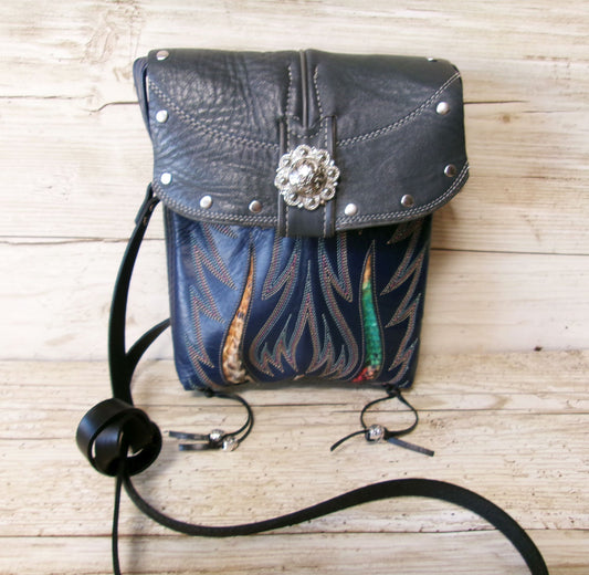 Blue leather bag with floral design and decorative elements on a wooden surface