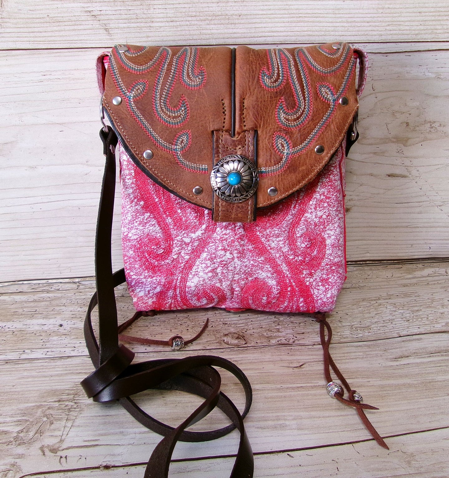 Pink and brown patterned handbag with a decorative clasp on a wooden surface