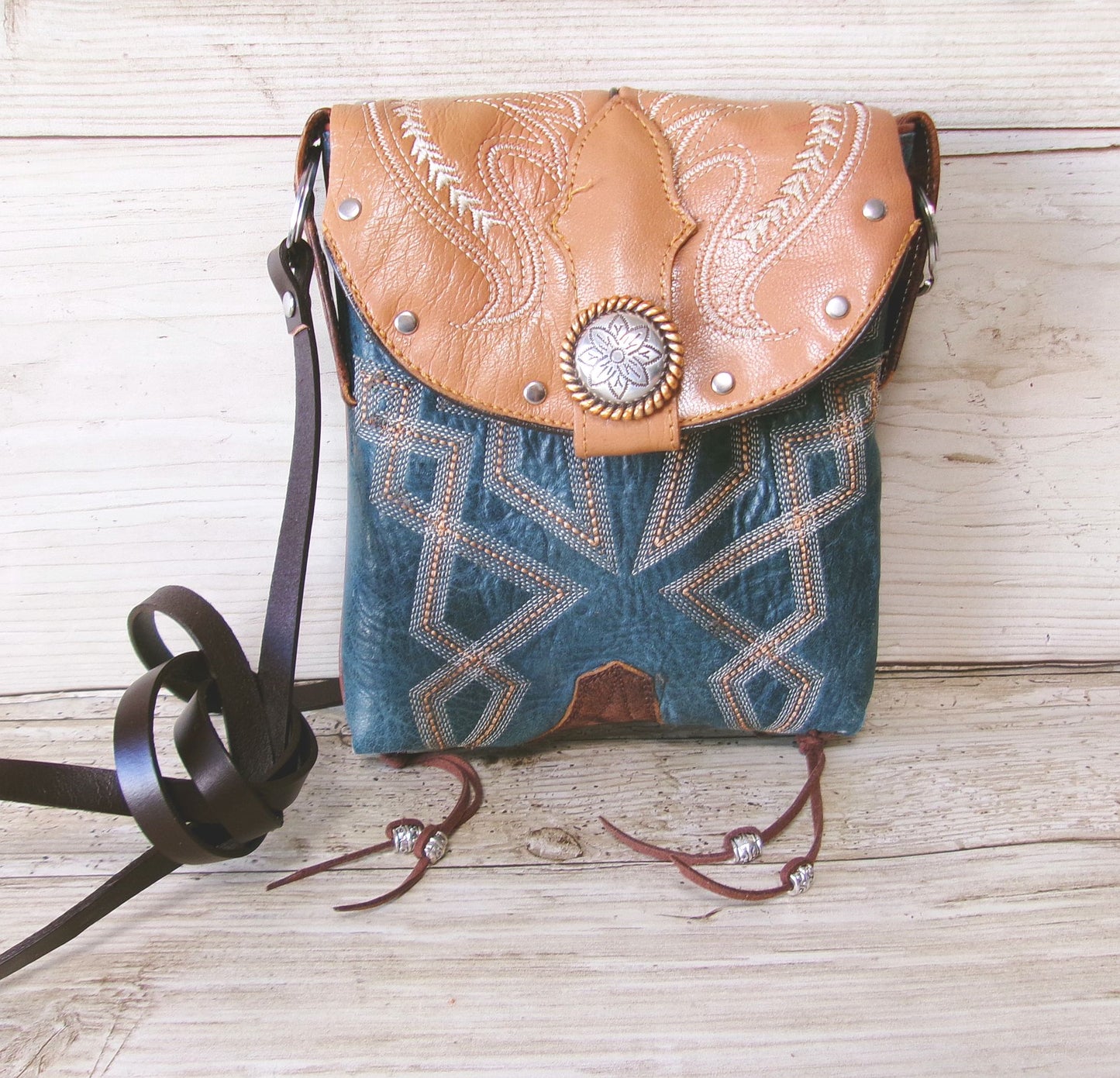 Brown and blue leather handbag with intricate patterns on a wooden surface