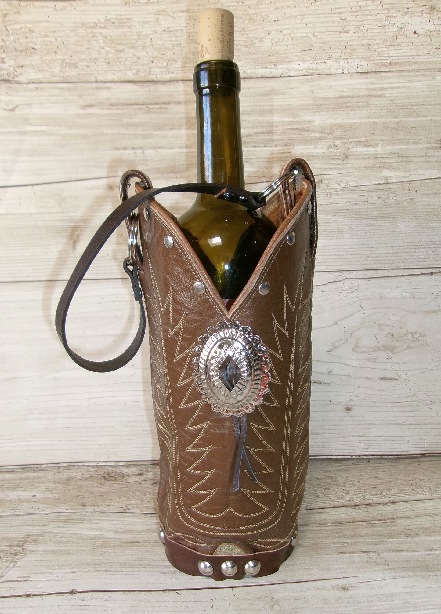Wine bottle in a decorative leather holder with metallic accents on a wooden surface