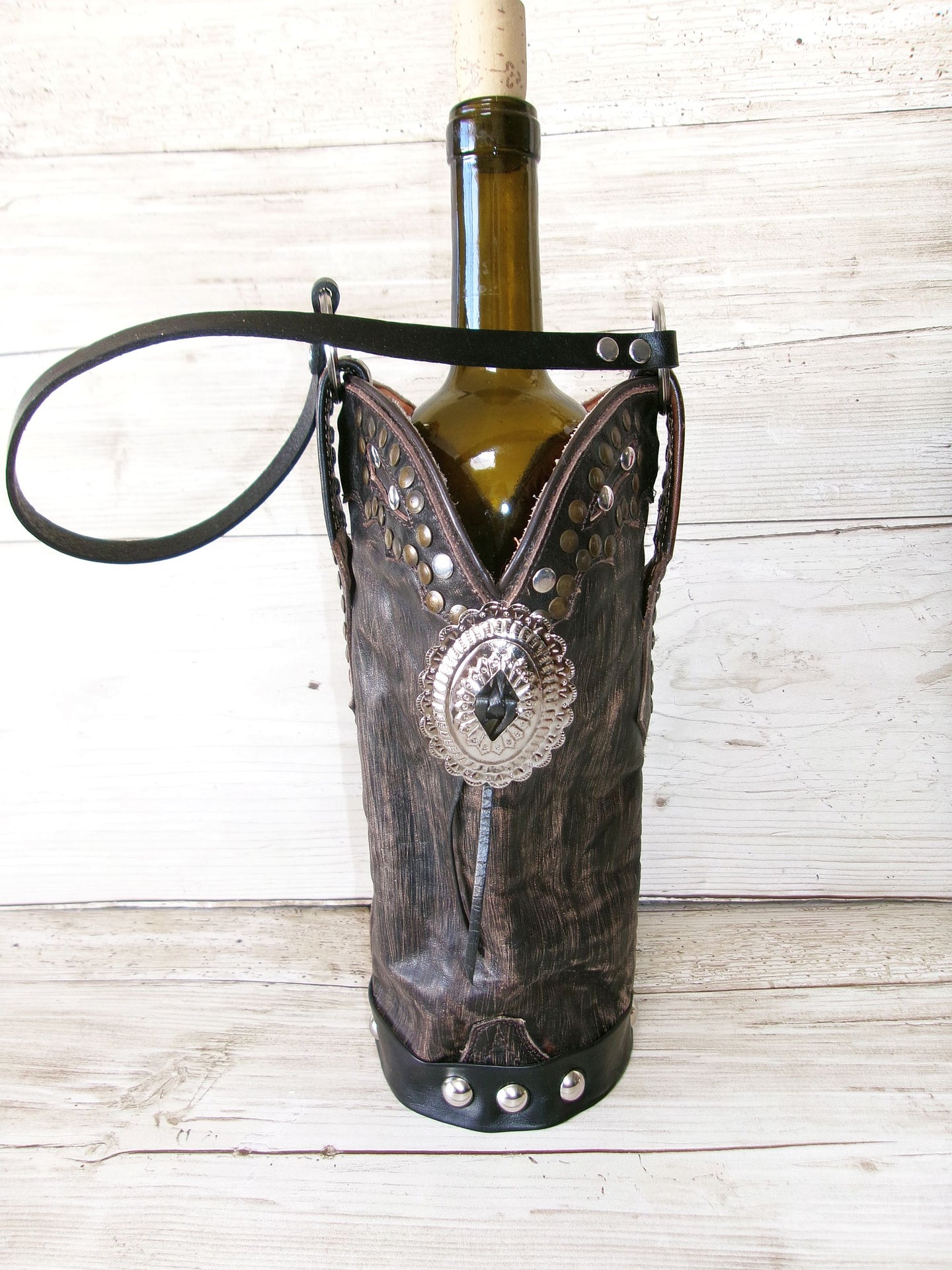 Wine bottle in a cowboy boot holder on a wooden surface