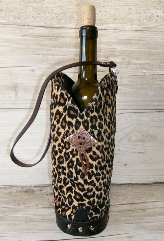 Wine bottle in a leopard print holder with a decorative emblem on a wooden surface