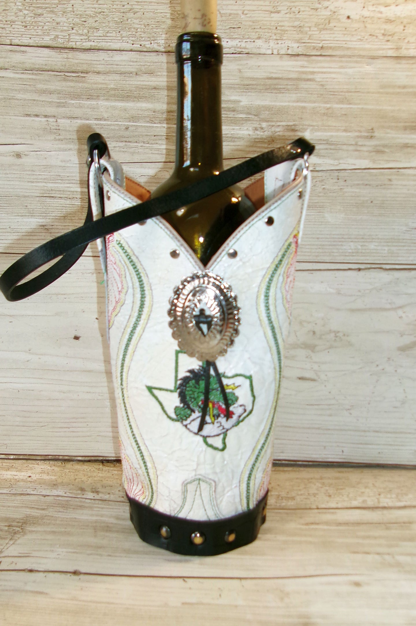 Wine bottle with decorative cover featuring a Texas map and face design on a wooden surface.