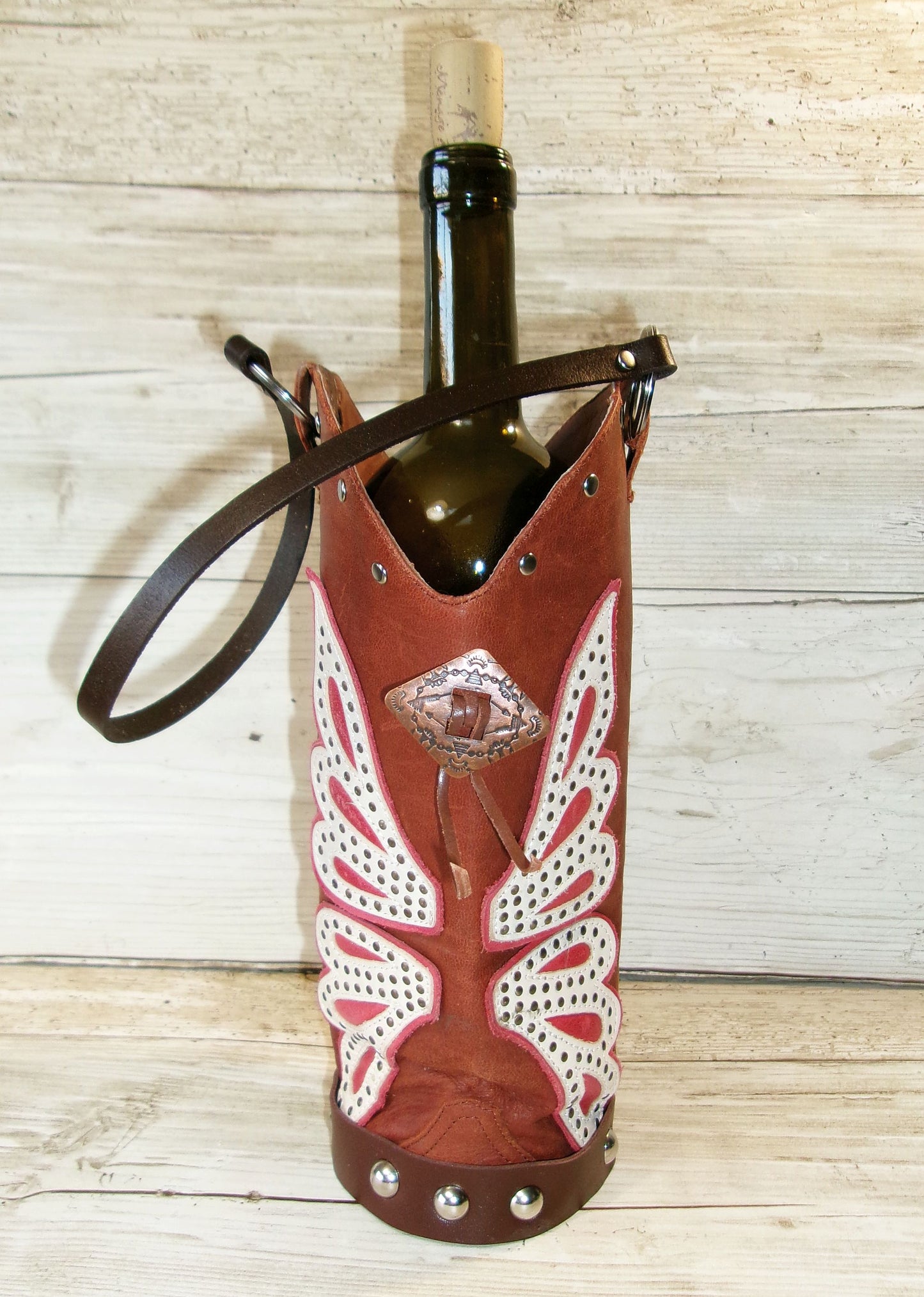 Wine bottle in a decorative leather holder on a wooden surface
