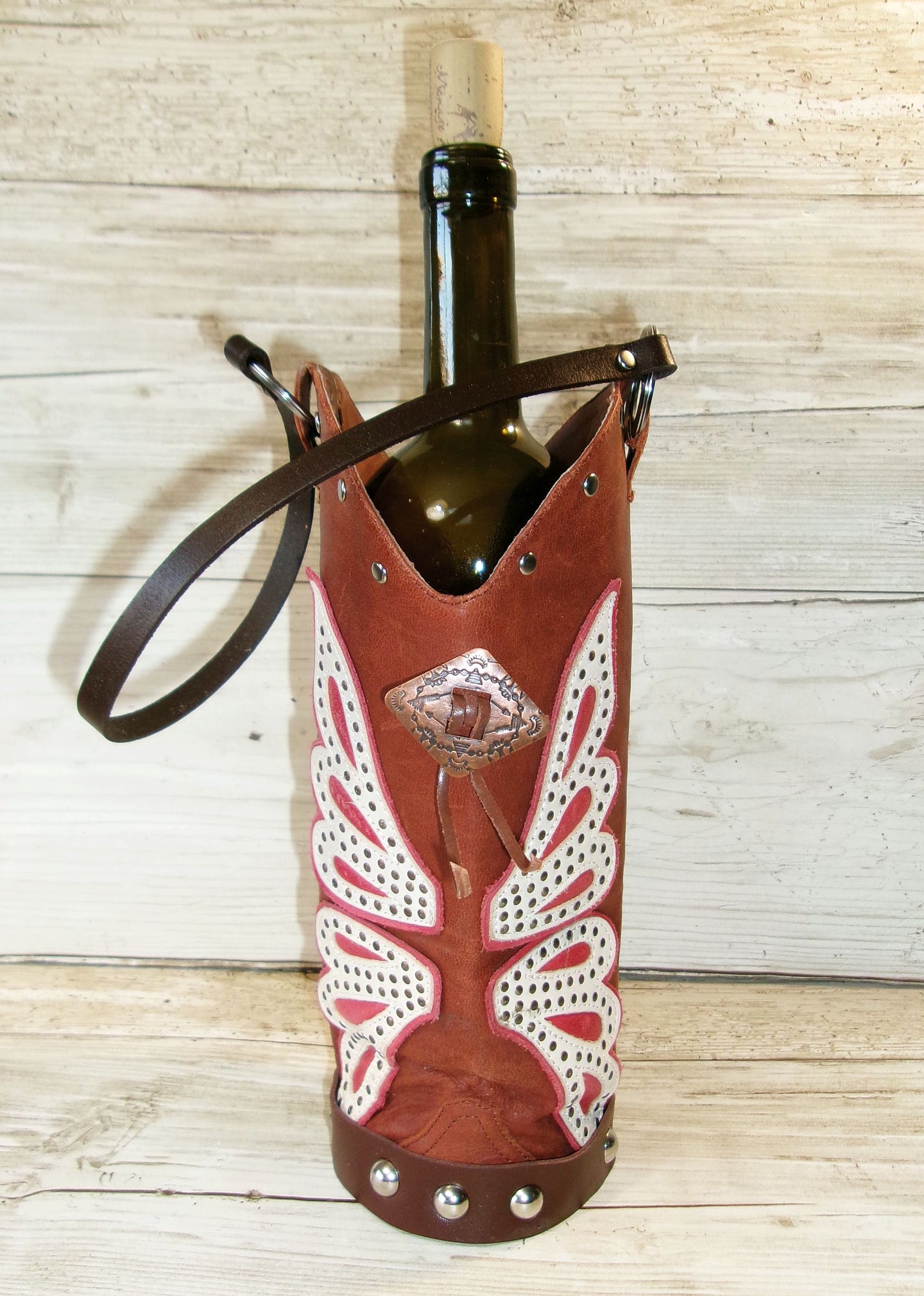Wine bottle in a decorative leather holder on a wooden surface