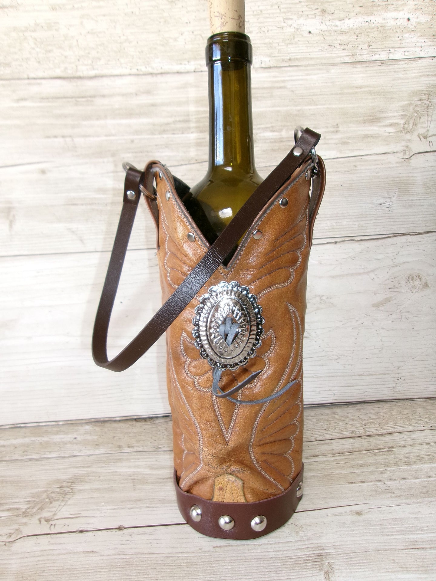 Cowboy boot-shaped wine bottle holder with a bottle of wine on a wooden surface
