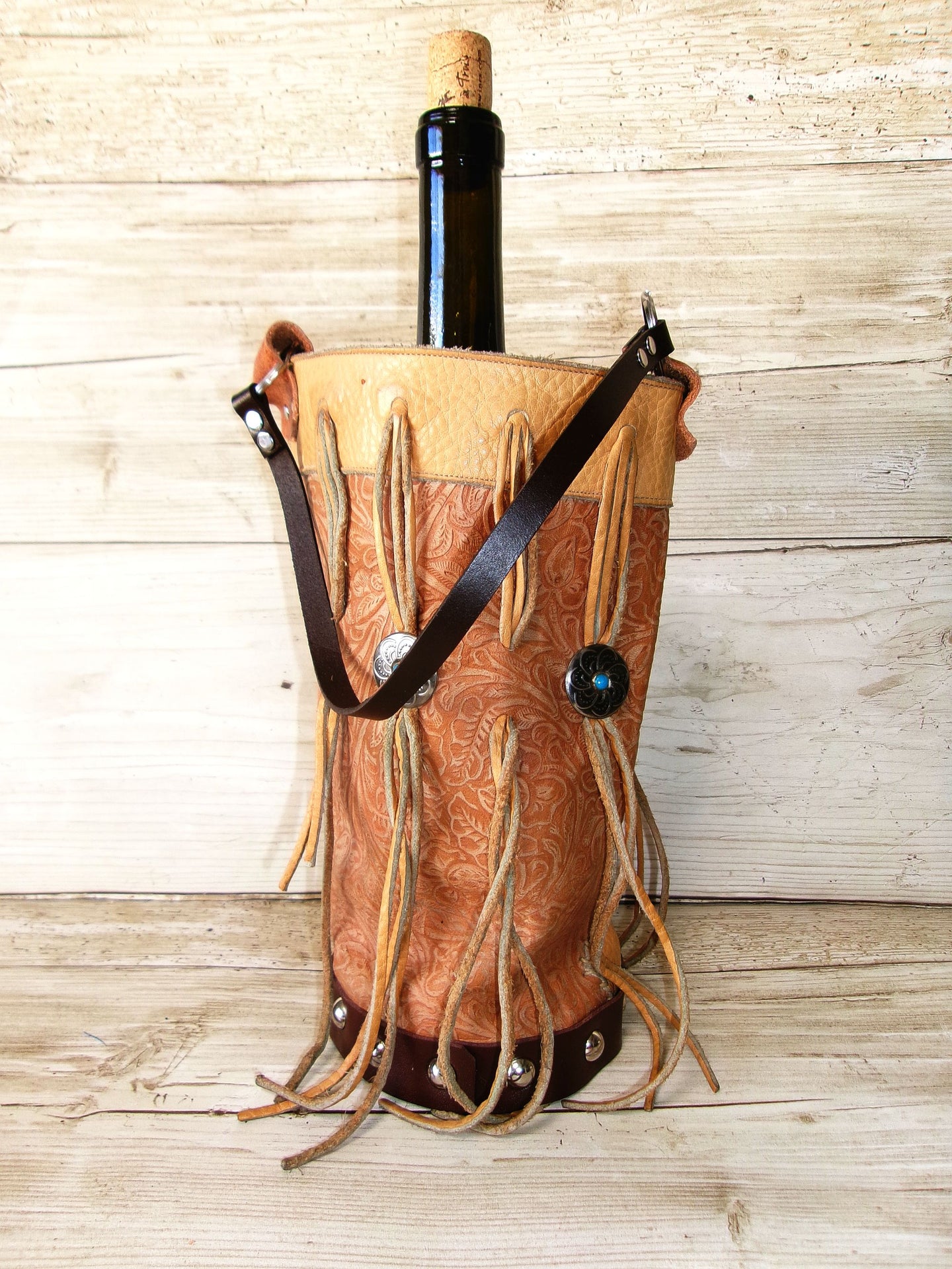 Wooden wine bottle holder with leather straps and decorative elements on a wooden background