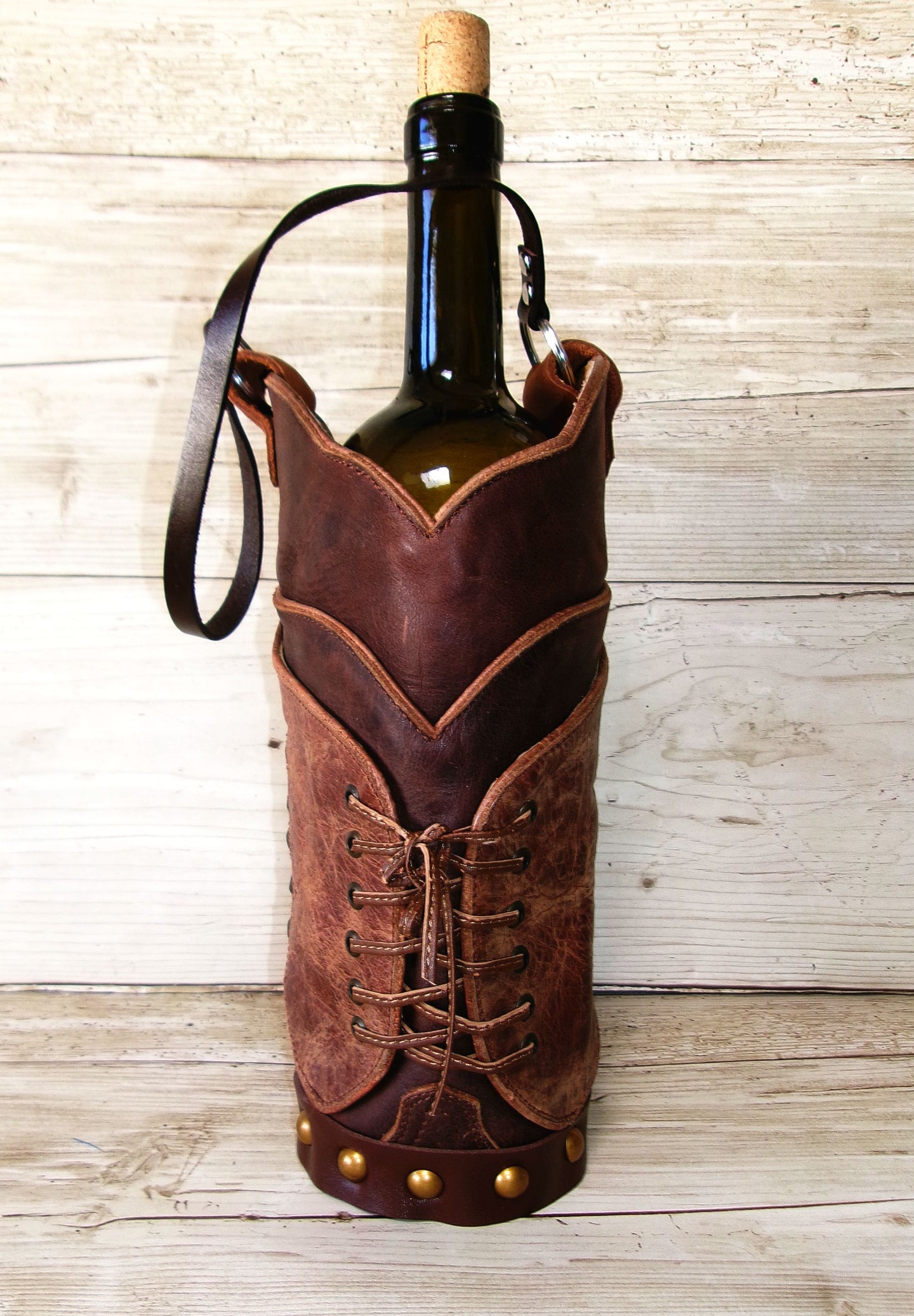 Brown leather wine bottle holder with a bottle of wine on a wooden surface