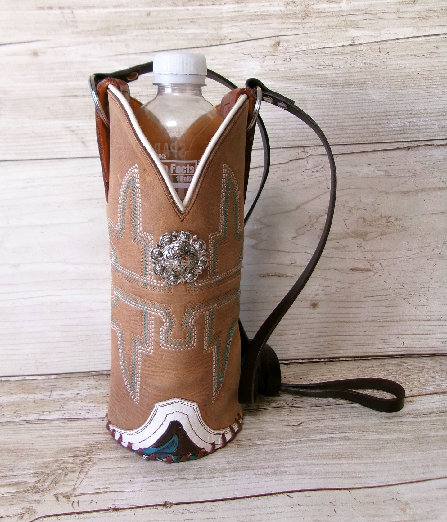 Cowboy boot-shaped bottle holder with decorative elements on a wooden surface