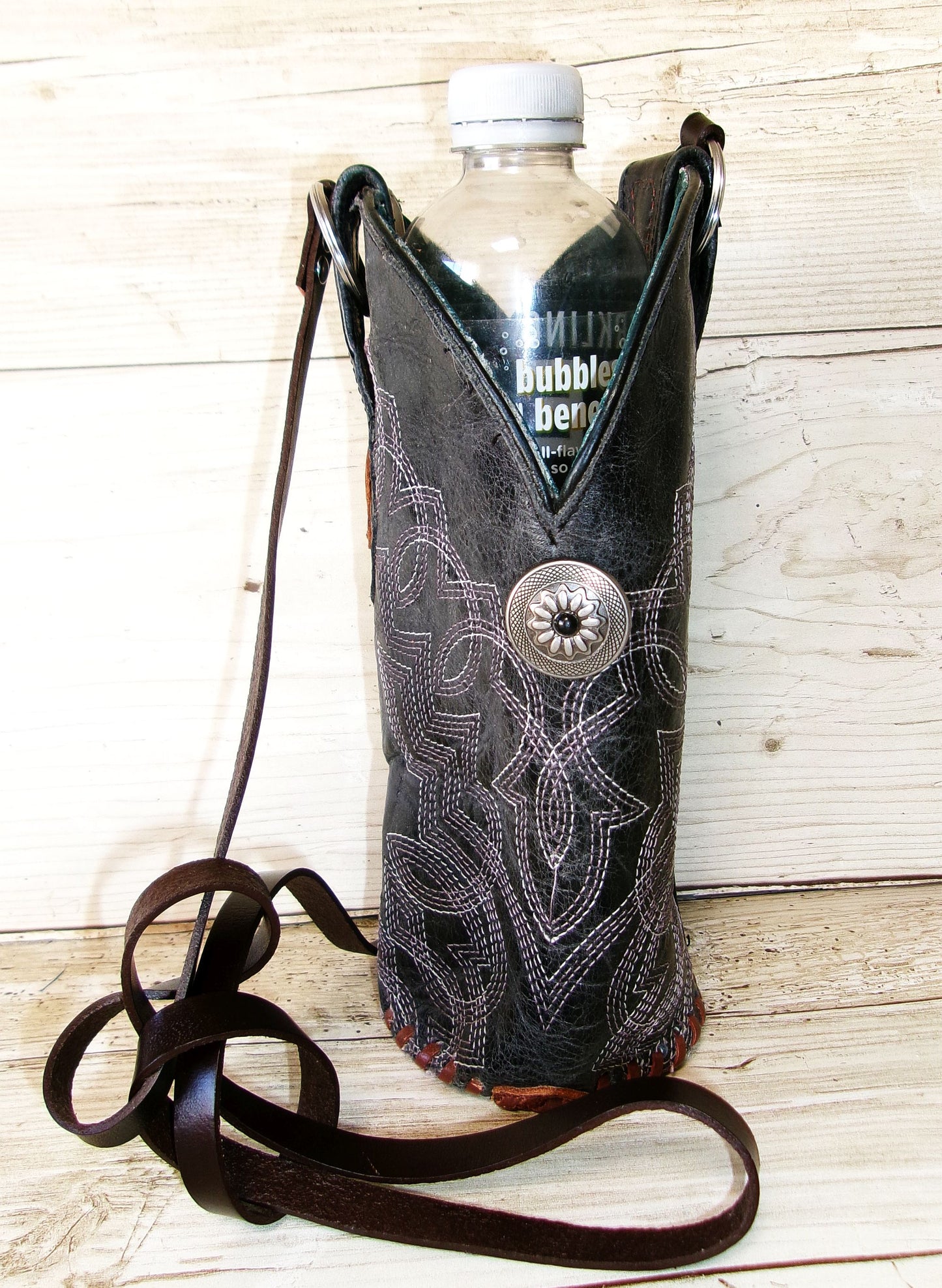 Cowboy boot-shaped bottle holder with a bottle on a wooden surface