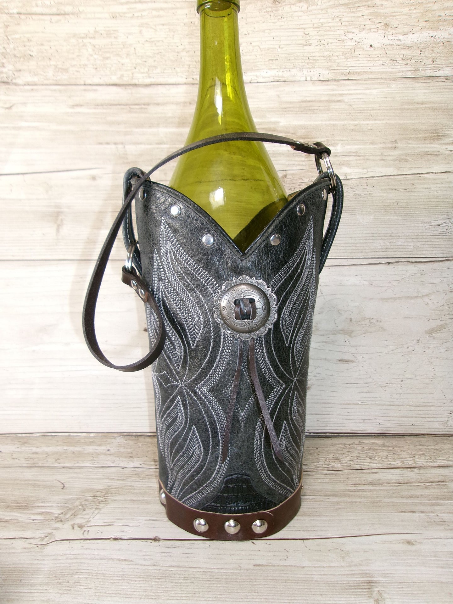 Decorative leather wine bottle holder with a bottle on a wooden surface