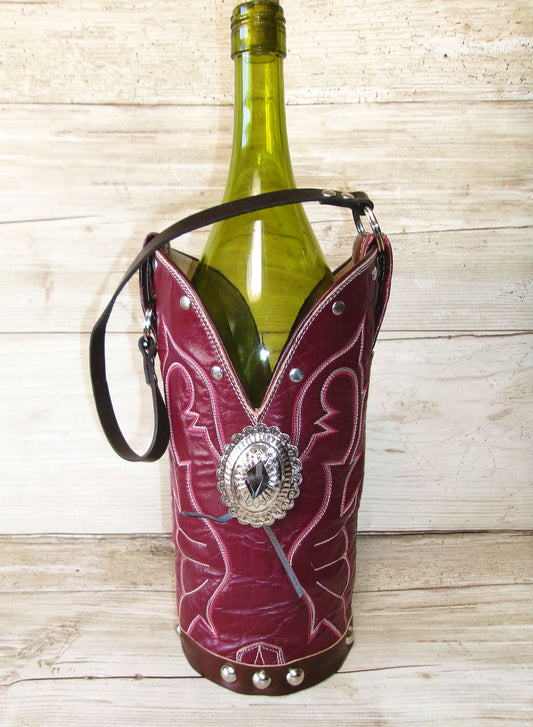 Red leather wine bottle holder with decorative concho on a wooden surface