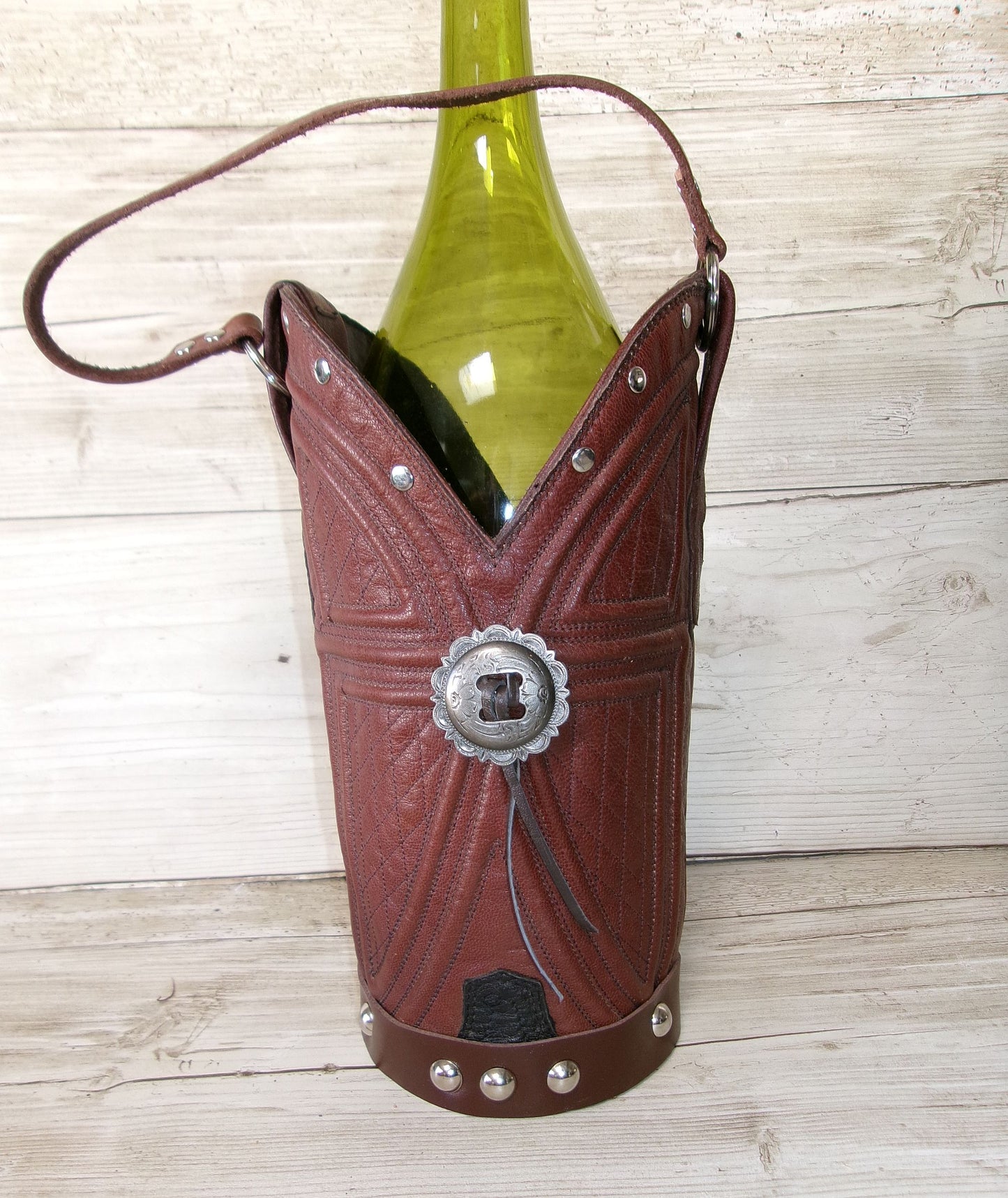 Cowboy boot-shaped wine bottle holder with a green bottle on a wooden surface