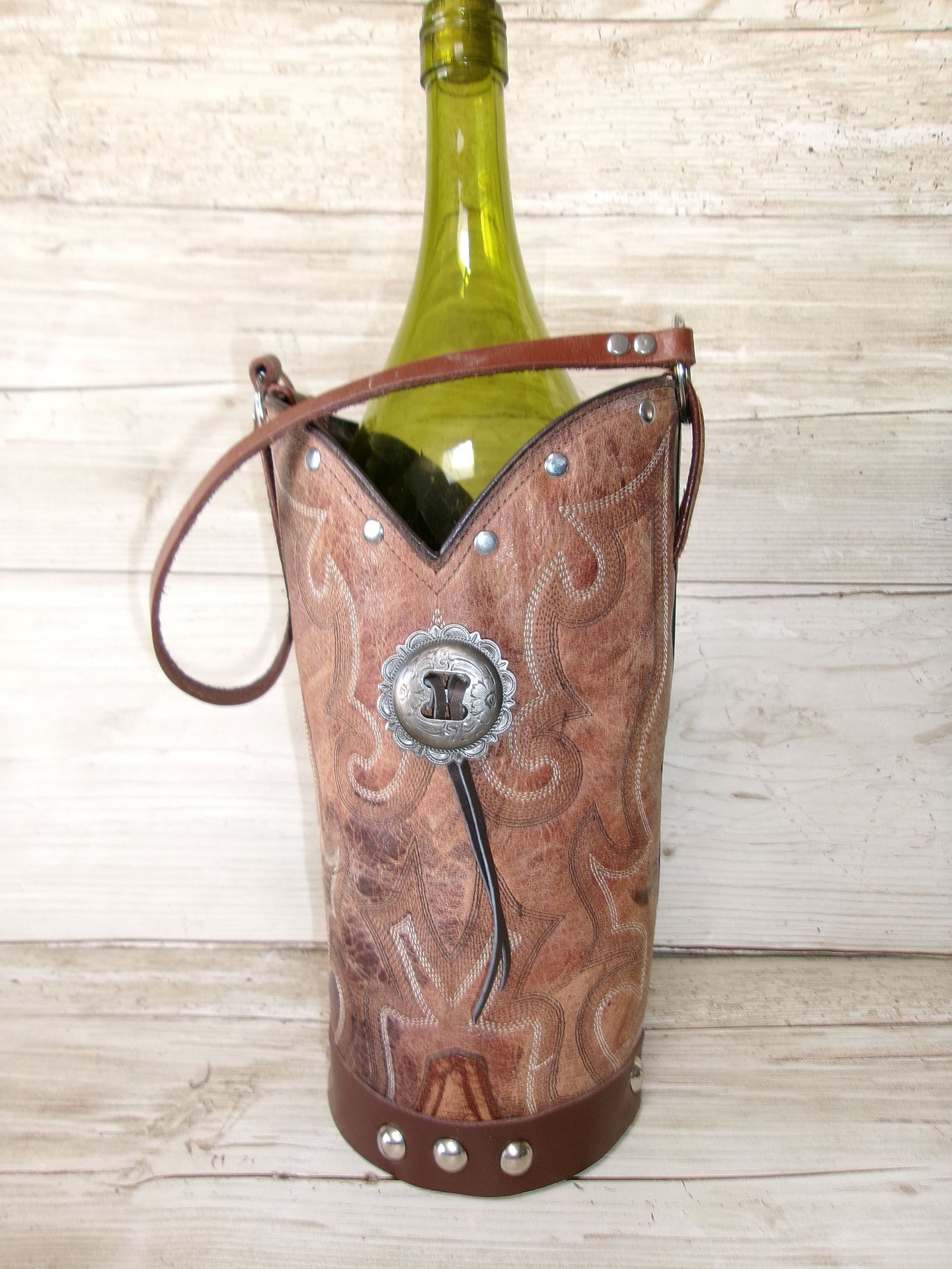 Cowboy boot-shaped wine bottle holder with a bottle of wine on a wooden surface
