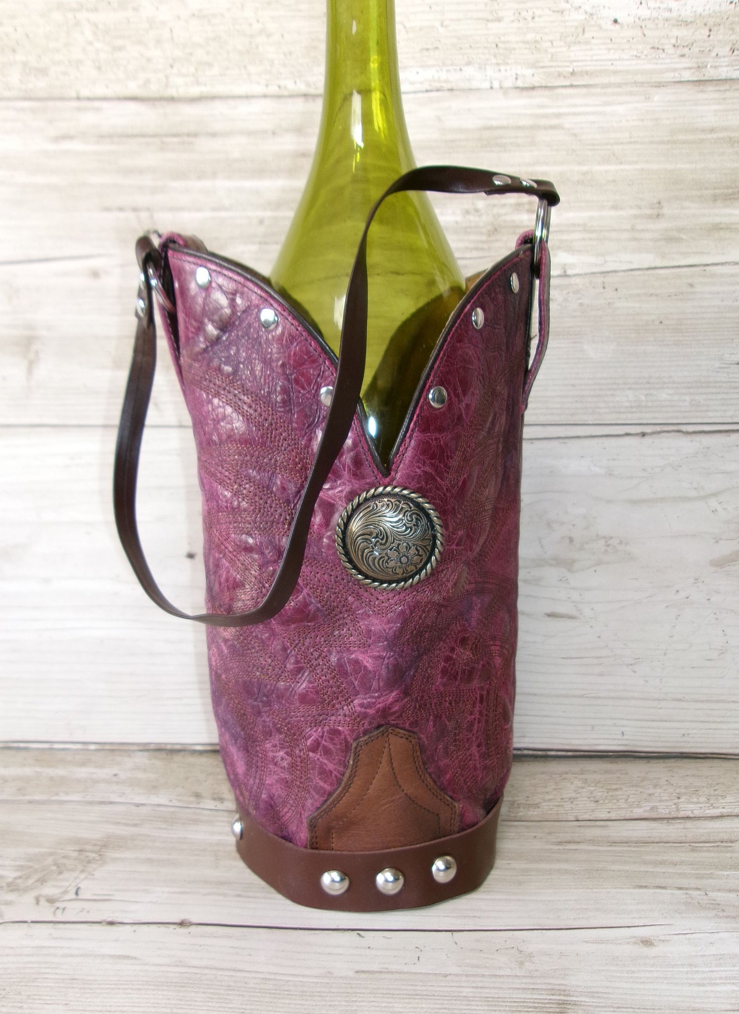 Pink cowgirl boot wine holder with a green bottle on a wooden surface