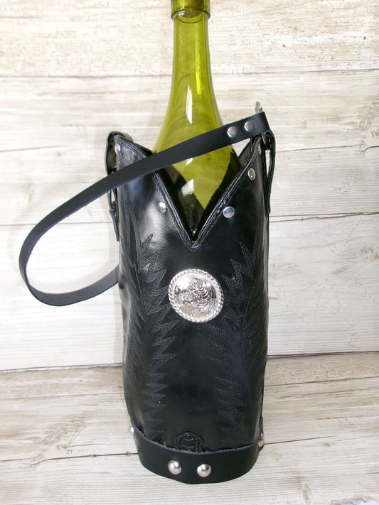 Black leather wine bottle holder with decorative concho on a wooden surface