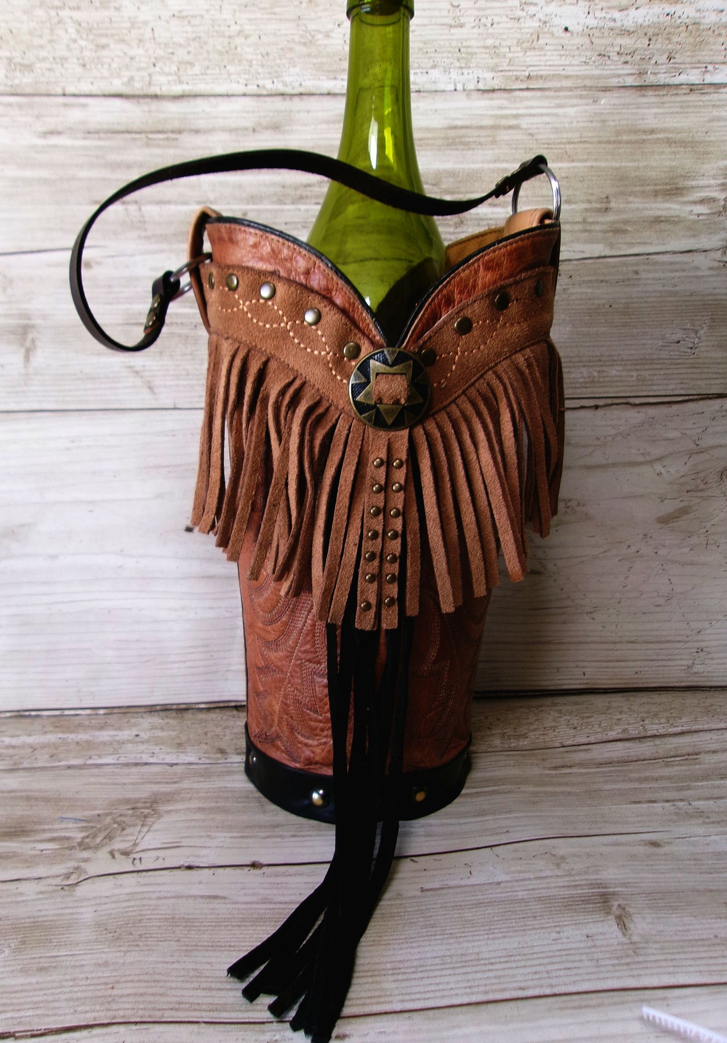 Bottle holder with fringes and studs on a wooden surface