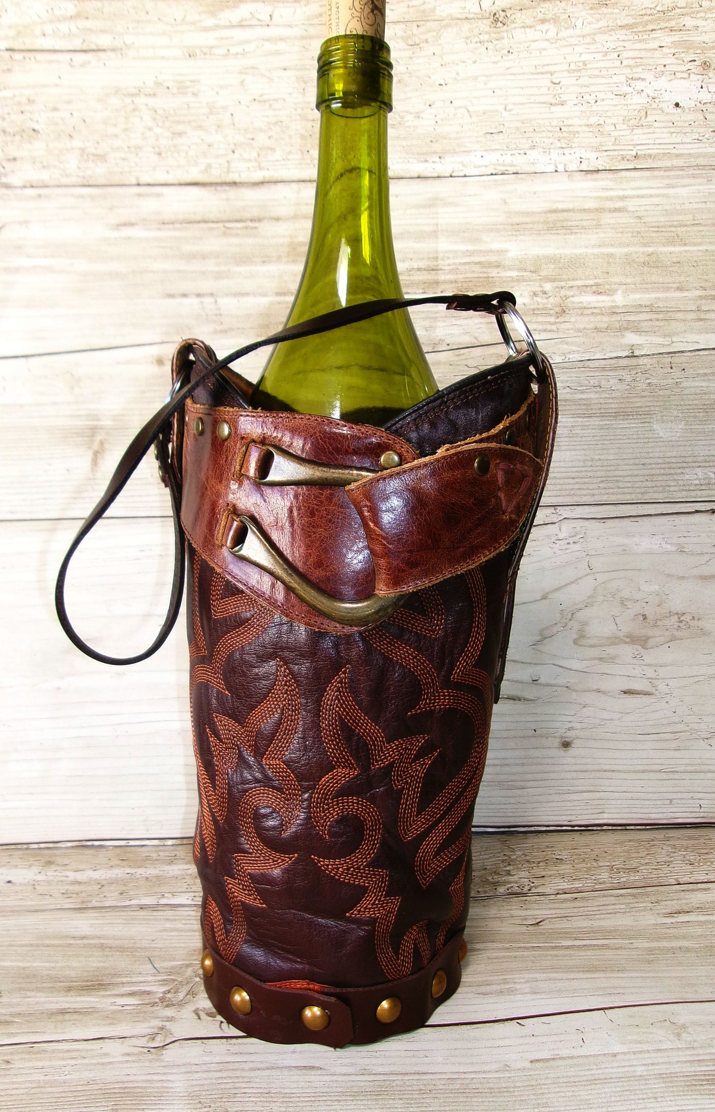 Wine bottle in a decorative leather holder on a wooden surface